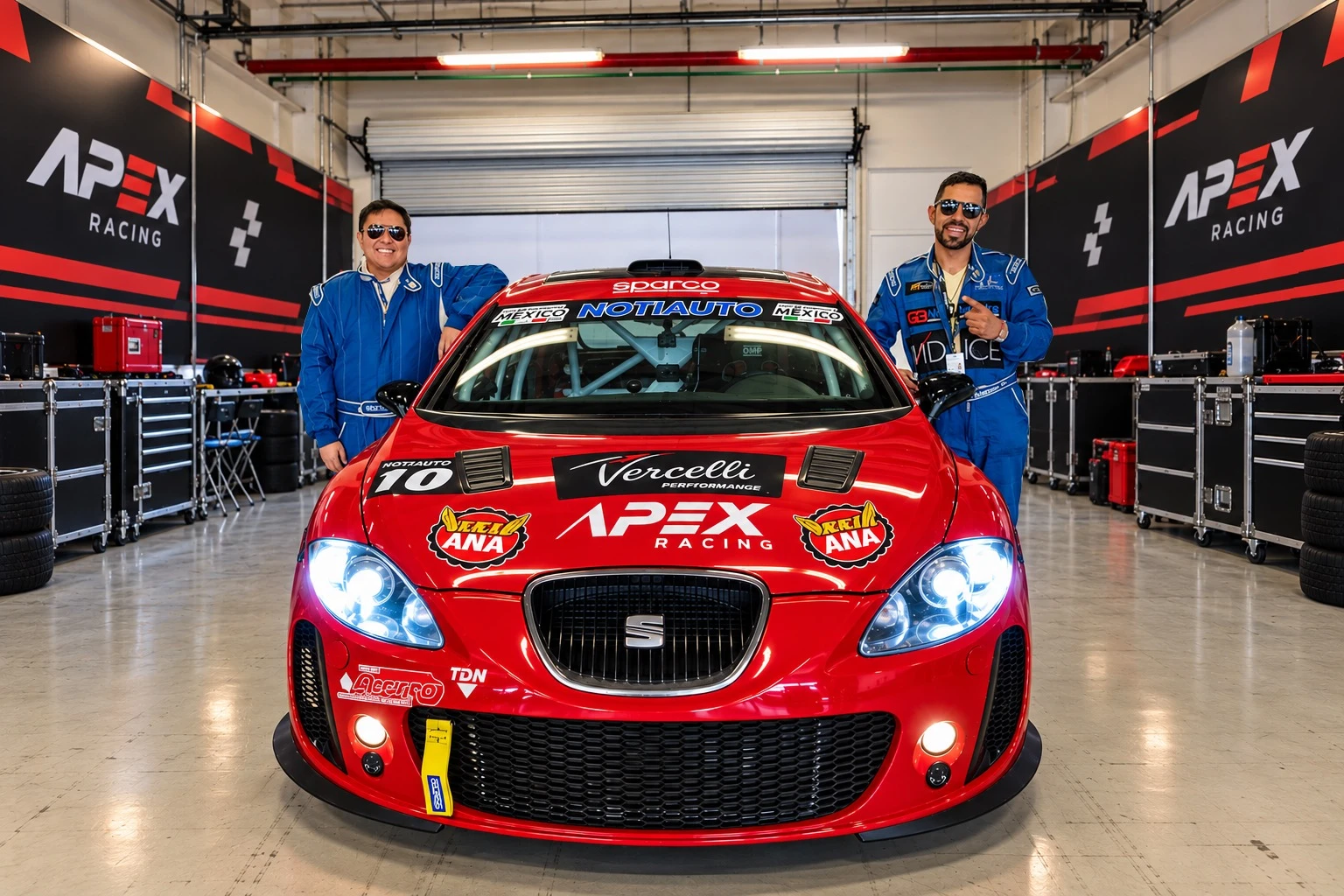 Dos pilotos de APEX Racing junto al SEAT de carreras rojo en el garaje