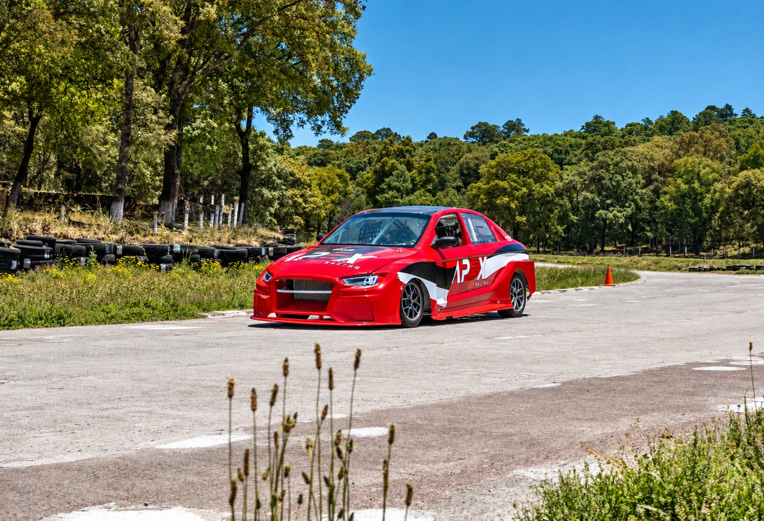 Auto rojo de APEX Racing en una pista rodeada de bosque